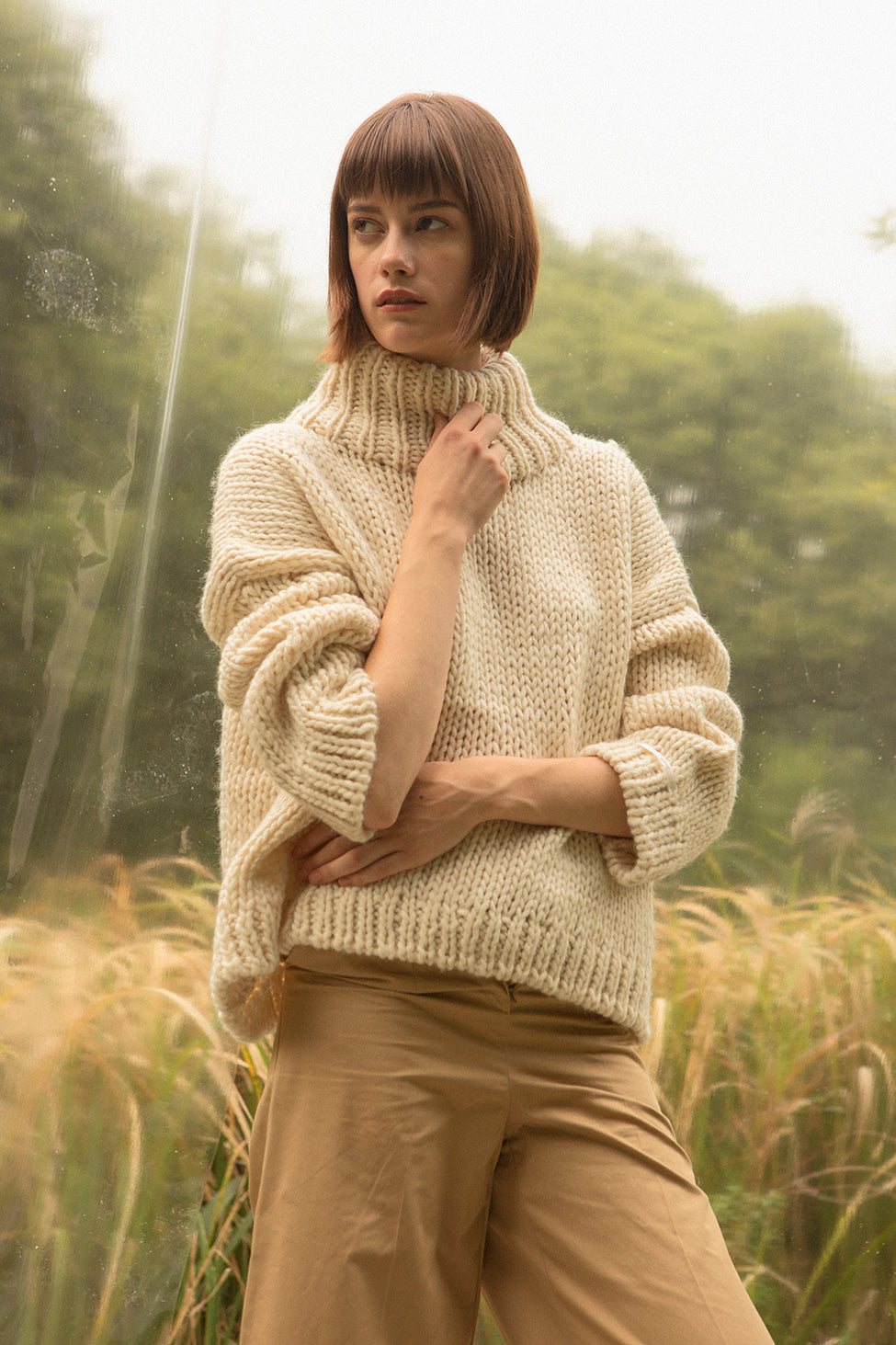 Open knit with turtleneck collar with dropped shoulders. Gently tapered long sleeves. Slightly cropped. Boxy silhouette. Relaxed fit.