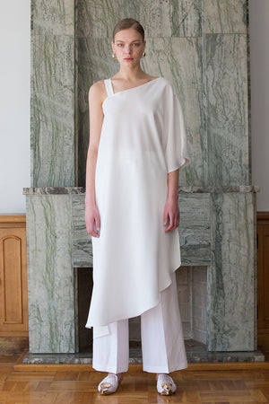 The Rowe Tunic in White. Cut out at one shoulder with D-ring adjustment. Asymmetric hem. Semi sheer. Pull on. 