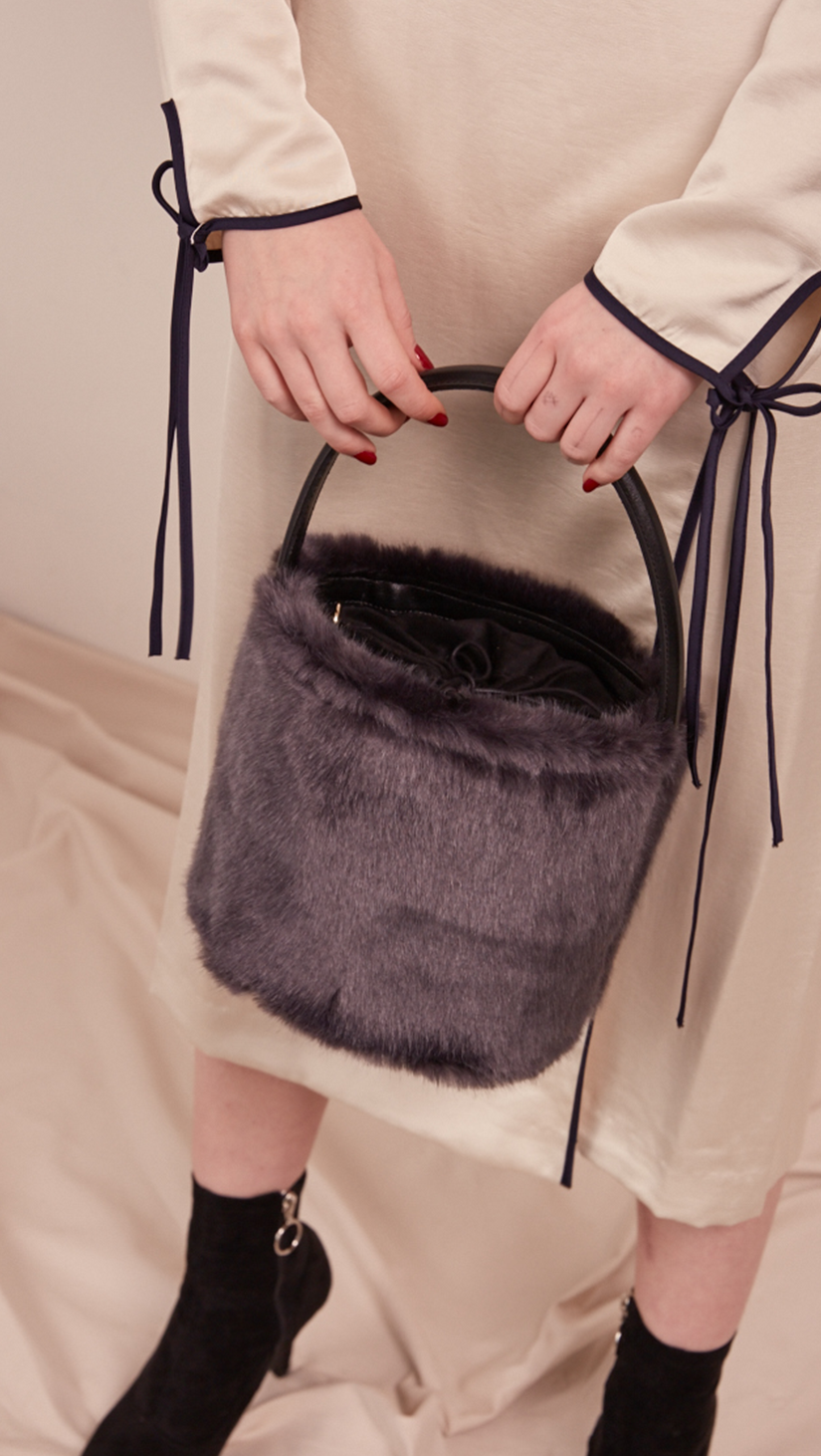Seed Furry Bucket bag in Lava Grey. Main compartment with adjustable strap, detachable shoulder strap, interior pocket with zipper compartment. Structured bottom.