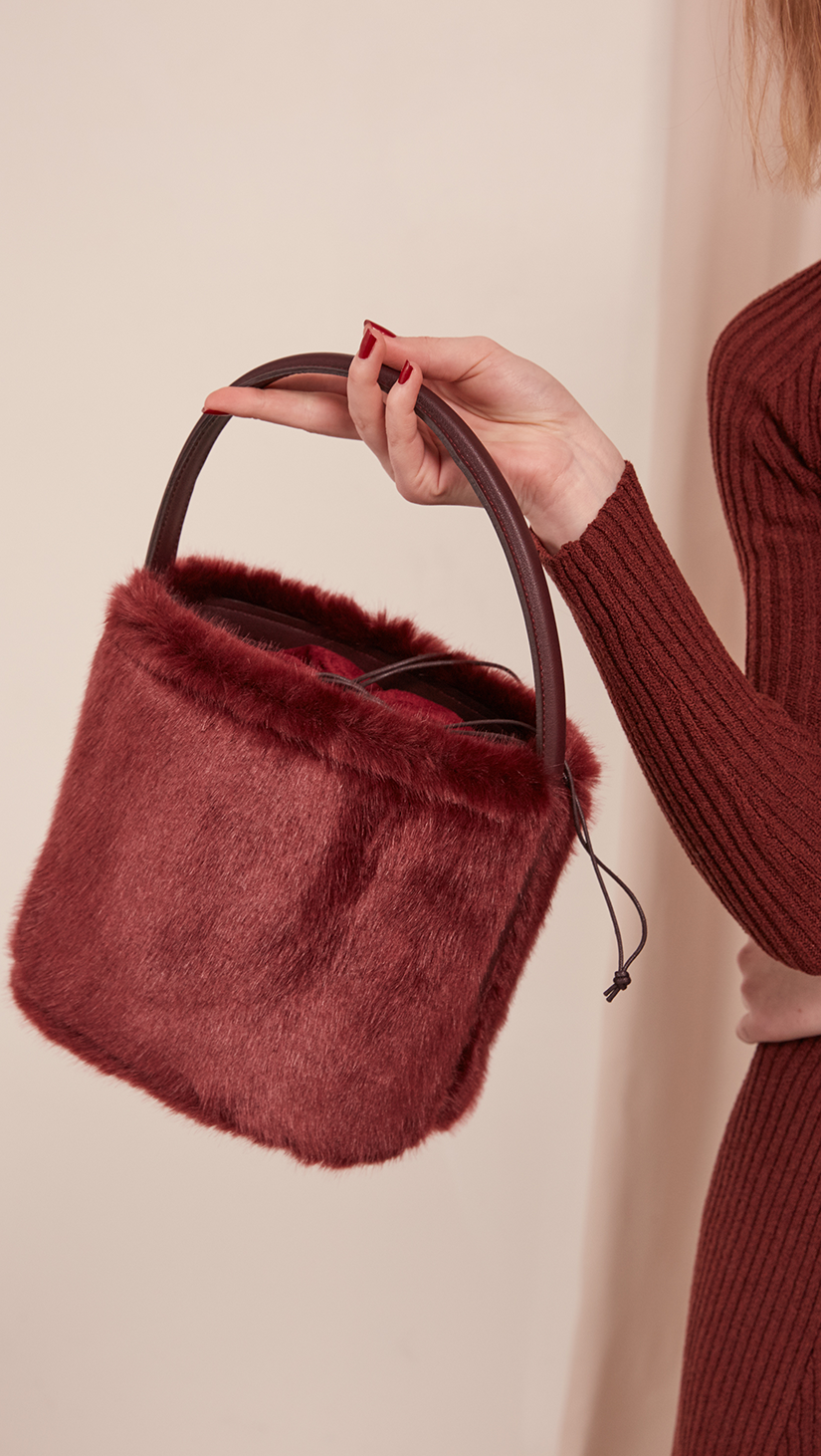 Seed Furry Bucket bag in Wine. Main compartment with adjustable strap, detachable shoulder strap, interior pocket with zipper compartment. Structured bottom.