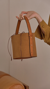 Seed Bucket bag in Tan. Main compartment with adjustable strap, detachable shoulder strap, interior pocket with zipper compartment. Structured bottom.