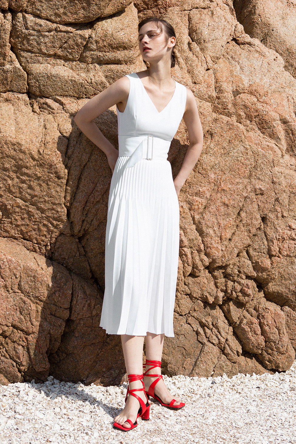 The Simma Dress in White, featuring v-neckline, sleeveless, removable wide belt, pleated skirt. Concealed zip fastening at the back. Fully lined.