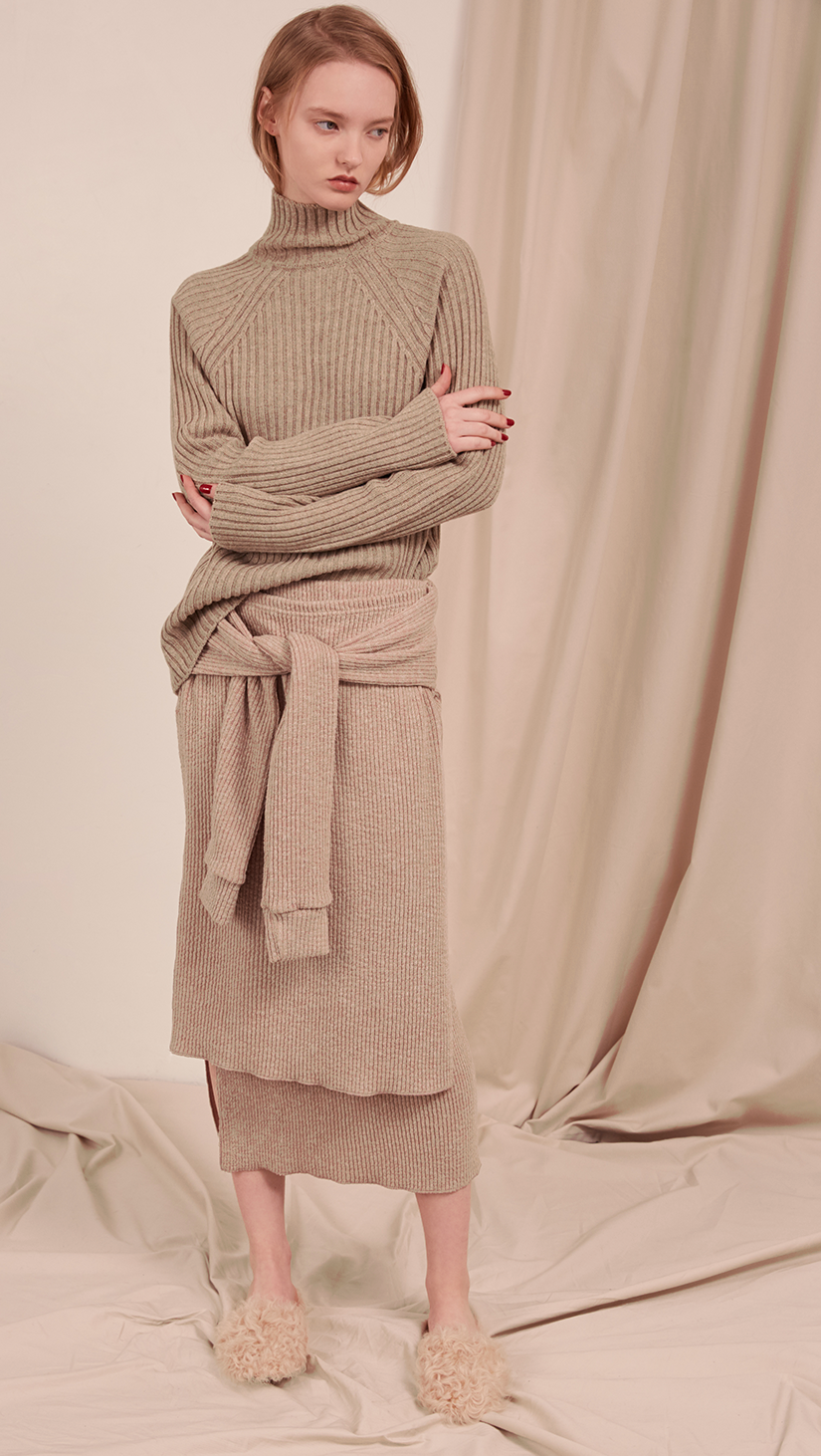 The Natalie Skirt in oatmeal beige. With double layer in ribbed knit, self wrap tie, gathered elastic waistband, deep side slits. Pull on.