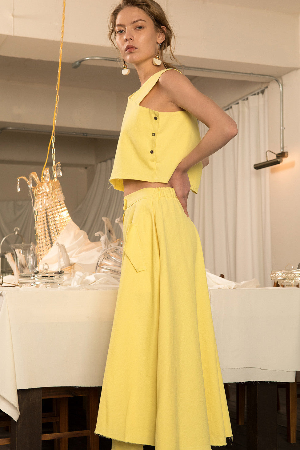 The Sonya set in Mustard, top featuring asymmetrical V-neckline, button closure along side. Skirt featuring slant pockets, asymmetrical hem in fluted edge, single button fastening with elasticated waistband, high waist in ankle length.