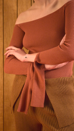 The Ellin OTS Sweater in Dusty Pink. Features off-the-shoulder silhouette with cut out cuffs. Pull on. Slim fit.