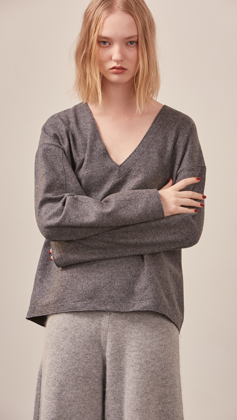 The Stiü wool blend sweater in dark grey with a deep V-neckline, long sleeves. Pull on. Lightweight. Non-stretchy. Relaxed fit. 