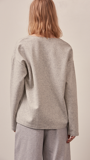 The Stiü wool blend sweater in light grey with a deep V-neckline, long sleeves. Pull on. Lightweight. Non-stretchy. Relaxed fit. 