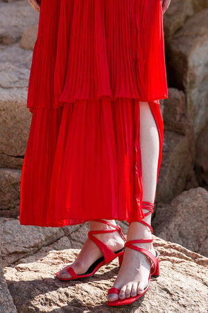 The Tellie Dress in Red, featuring off the shoulder neckline with elastic band, short sleeveless with gathered ruffles. Button down closure with side slits. Pull on.