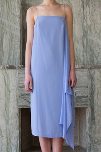 The Valerian Dress in Blue. Thin straps. Square neckline. Handkerchief hem. Below-the-knee length. Unlined.