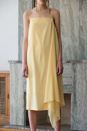 The Valerian Dress in Sun. Thin straps. Square neckline. Handkerchief hem. Below-the-knee length. Unlined.