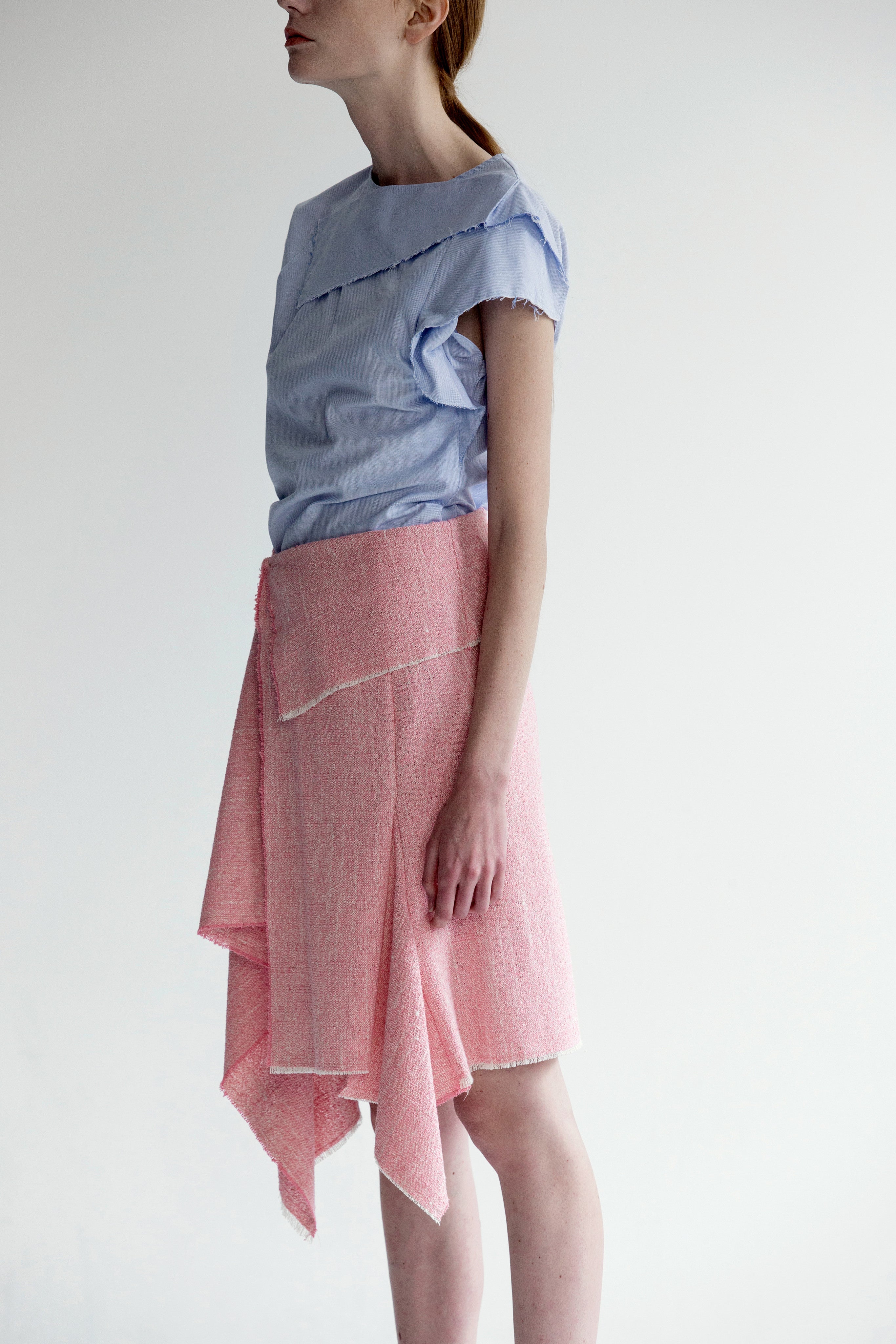 The Vernon Skirt in Pink featuring cascading ruffle down front. Asymmetrical hem. Wrapover front panel with two snap button. Front vent.