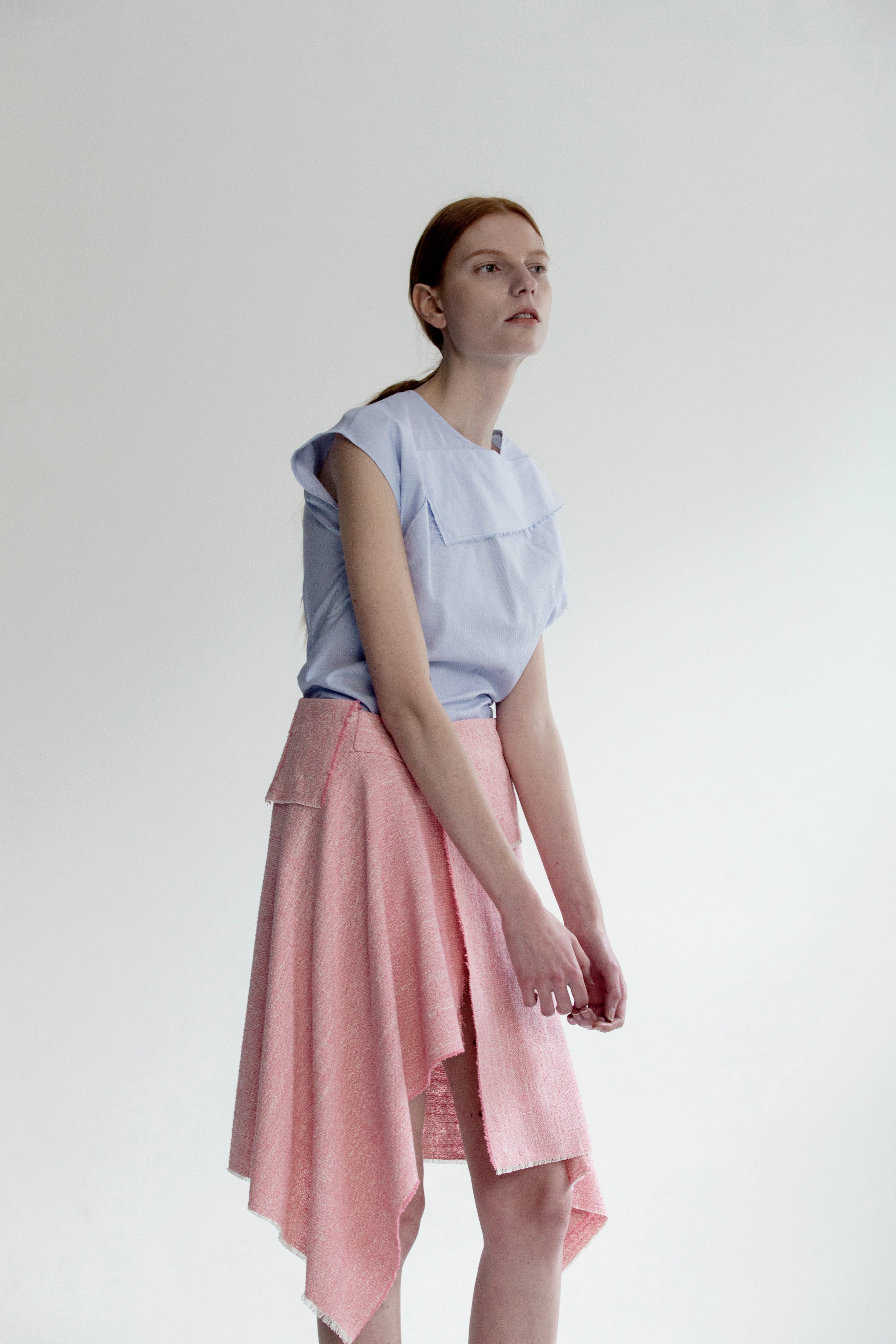 The Vernon Skirt in Pink featuring cascading ruffle down front. Asymmetrical hem. Wrapover front panel with two snap button. Front vent.