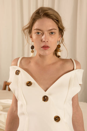 The Viveiro Dress in White, featuring deep V-neckline, half sleeves with large shoulder cutouts, button placket detailing throughout wth asymmetric ruffle flared hem.