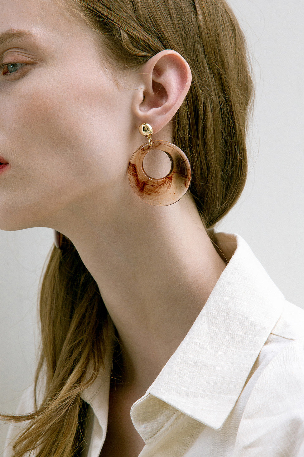 The Sossie, a pair of clear swirl earring in oval shape. Gold metal post back. Sold as a set.