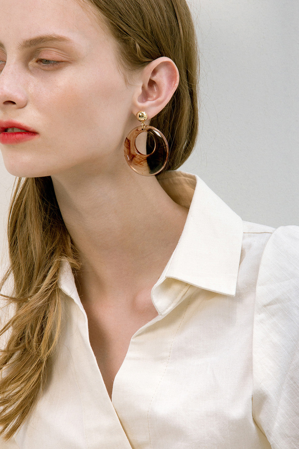 The Sossie, a pair of clear swirl earring in oval shape. Gold metal post back. Sold as a set.